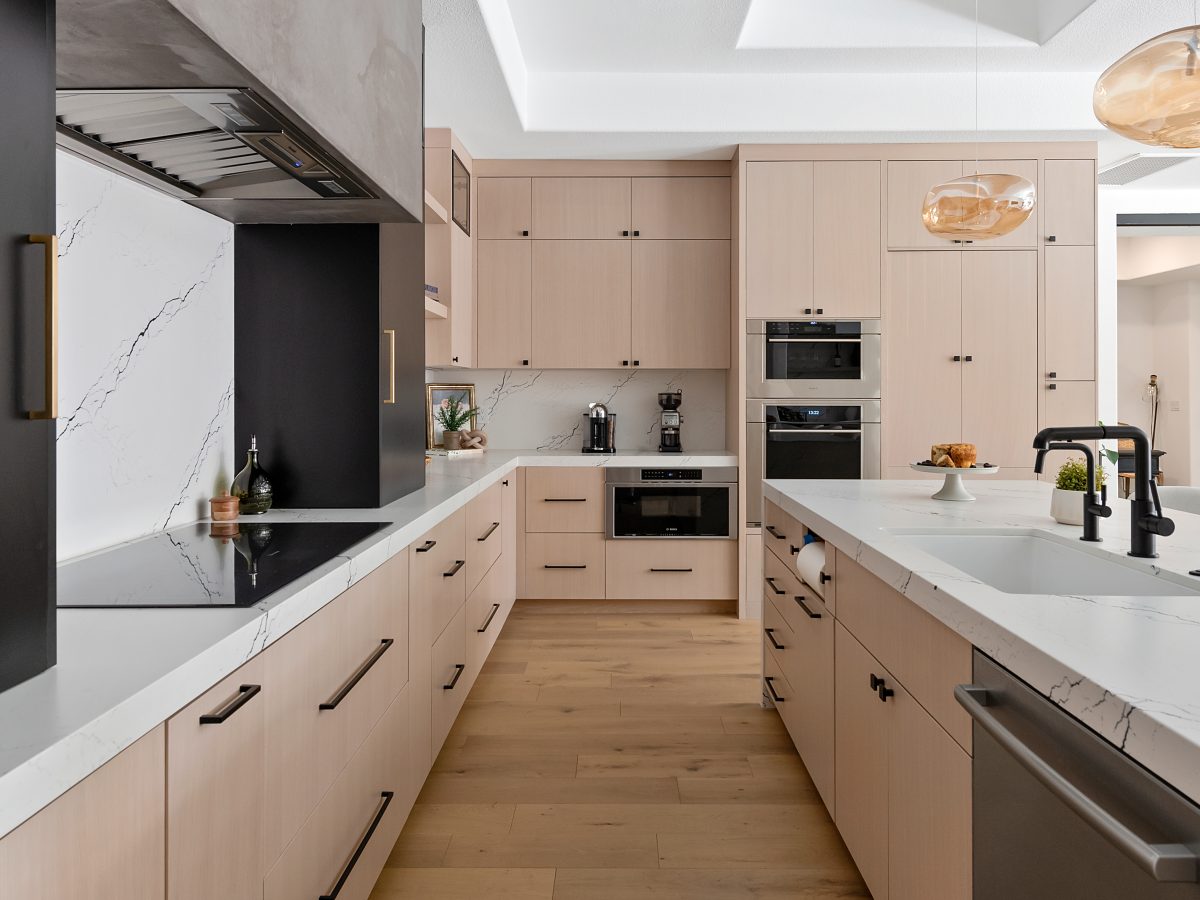 Modern kitchen with whitewashed oak cabinetry, black-veined white quartz countertops, and matte black accents — Reveal Interior Design Las Vegas