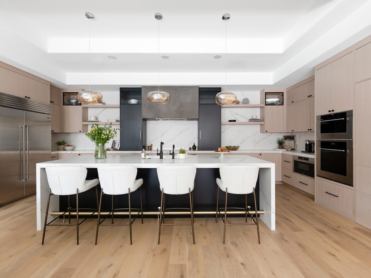 Modern kitchen with white-washed oak cabinetry, black quartz countertops, and warm engineered oak flooring — Reveal Interior Design Las Vegas
