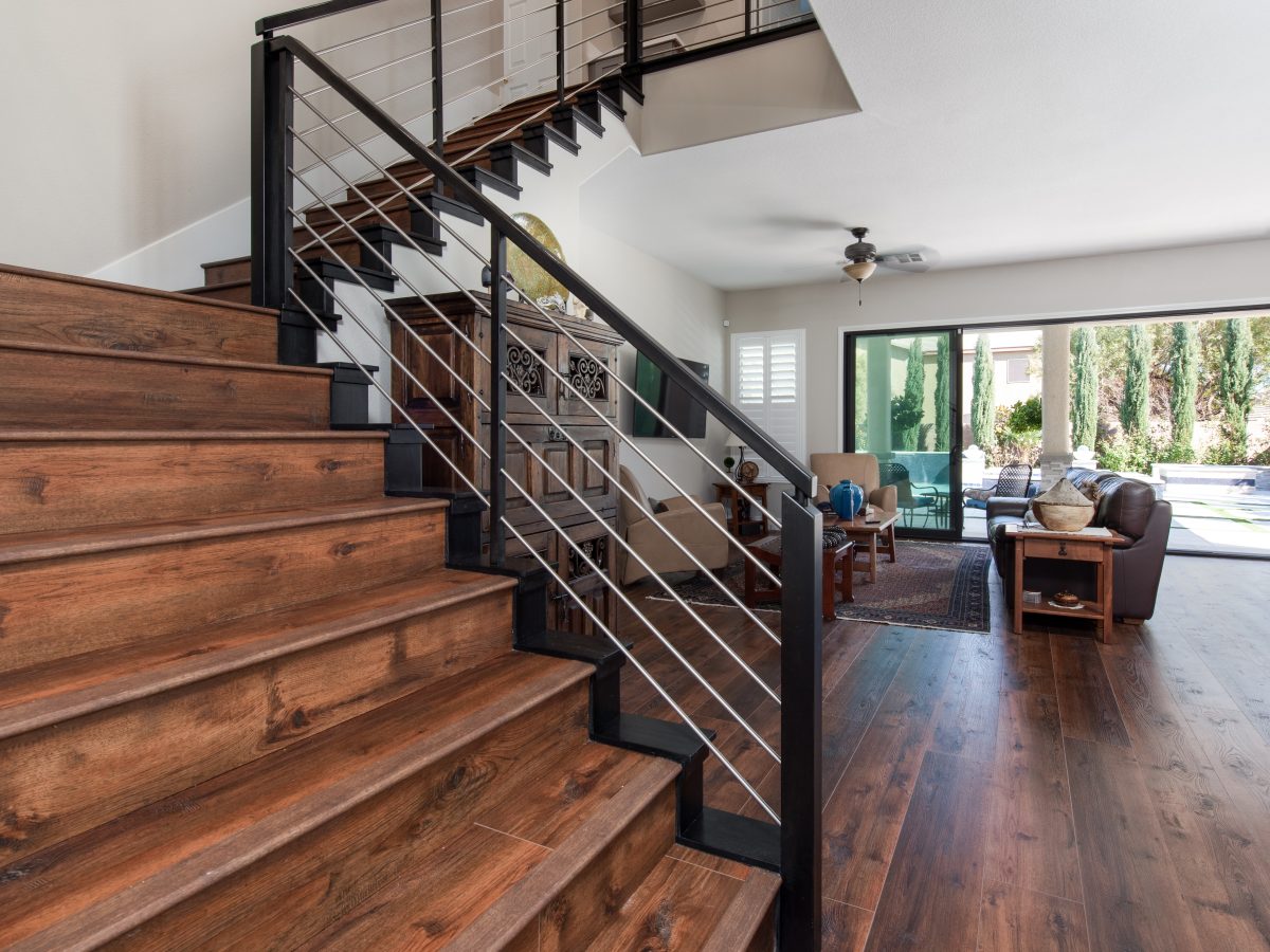 Living room with black metal cable stair railing and expansive black-trimmed sliding door — Reveal Interior Design Las Vegas