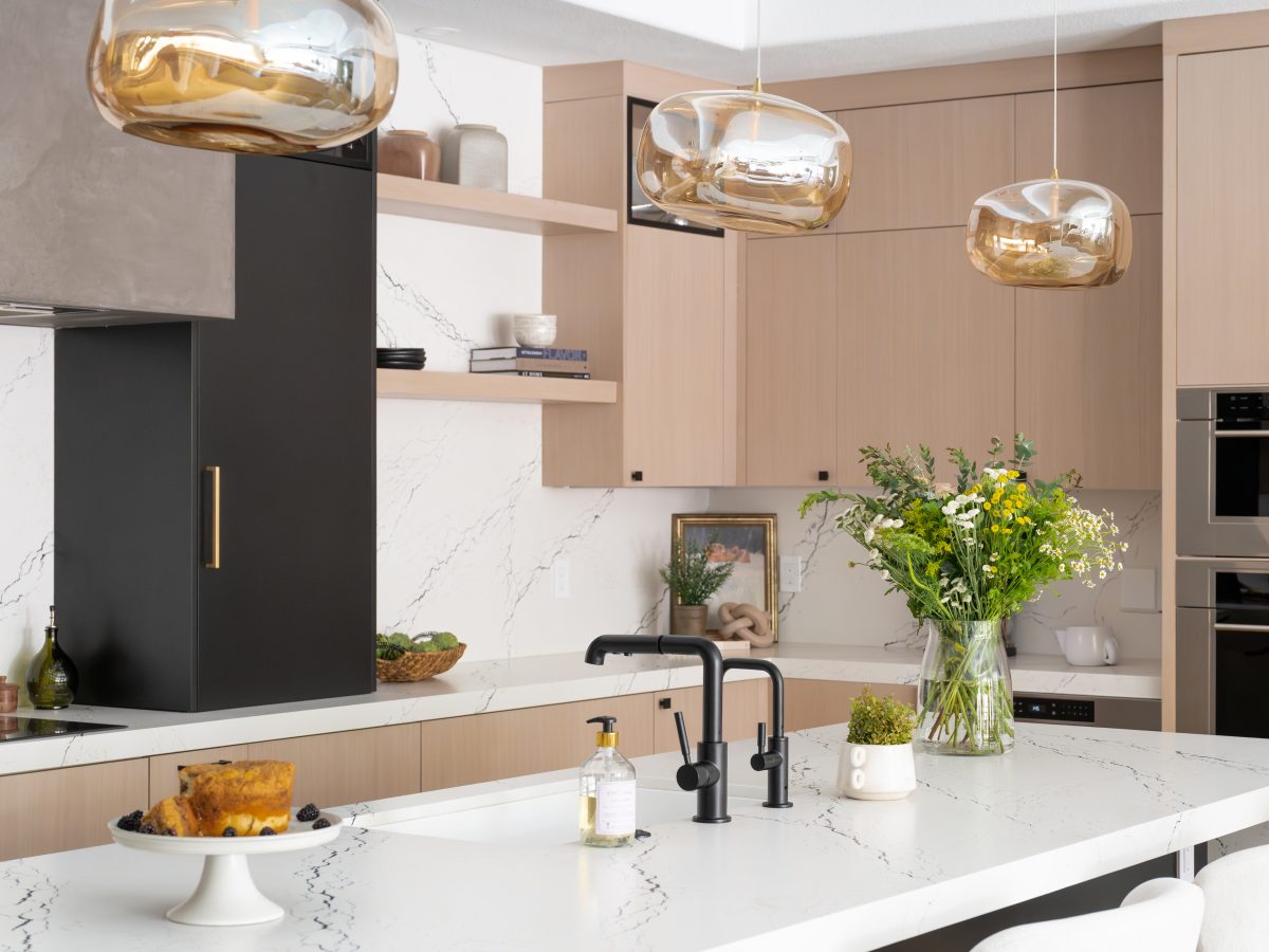 Contemporary kitchen with white-washed oak cabinetry, black quartz countertops, and amber glass pendants — Reveal Interior Design Las Vegas
