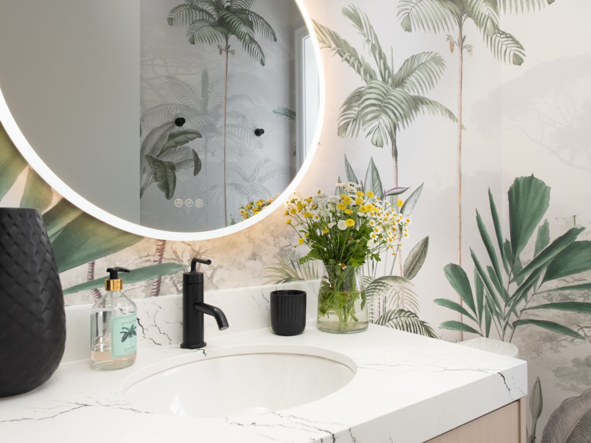 Tropical mural powder bath with stone vanity countertop and round LED mirror — Reveal Interior Design Las Vegas