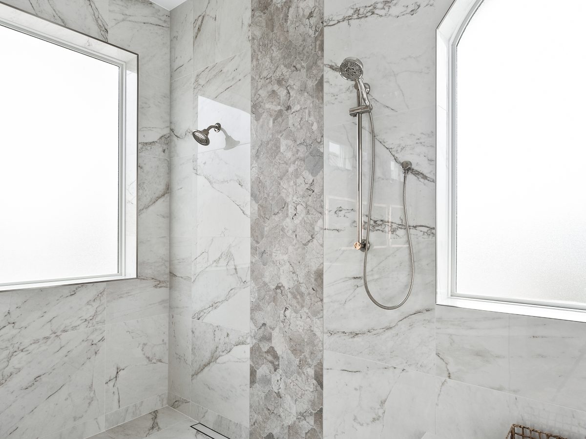 Transitional wet room with marble-look porcelain tile, polished nickel fixtures, and floating bench — Reveal Interior Design Las Vegas