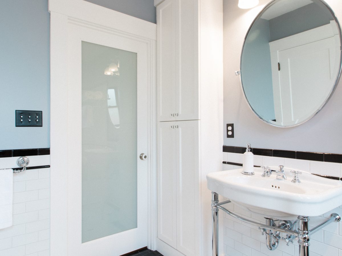 Historic 1920s black-and-white bathroom with hex mosaic floor and freestanding chrome sink — Reveal Interior Design Las Vegas