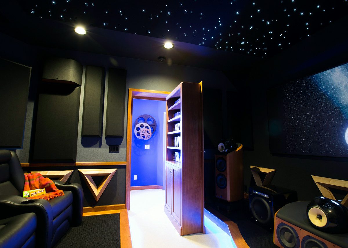 Home theater with fiber optic star ceiling, sound panels, and hidden maple bookcase door — Reveal Interior Design Las Vegas