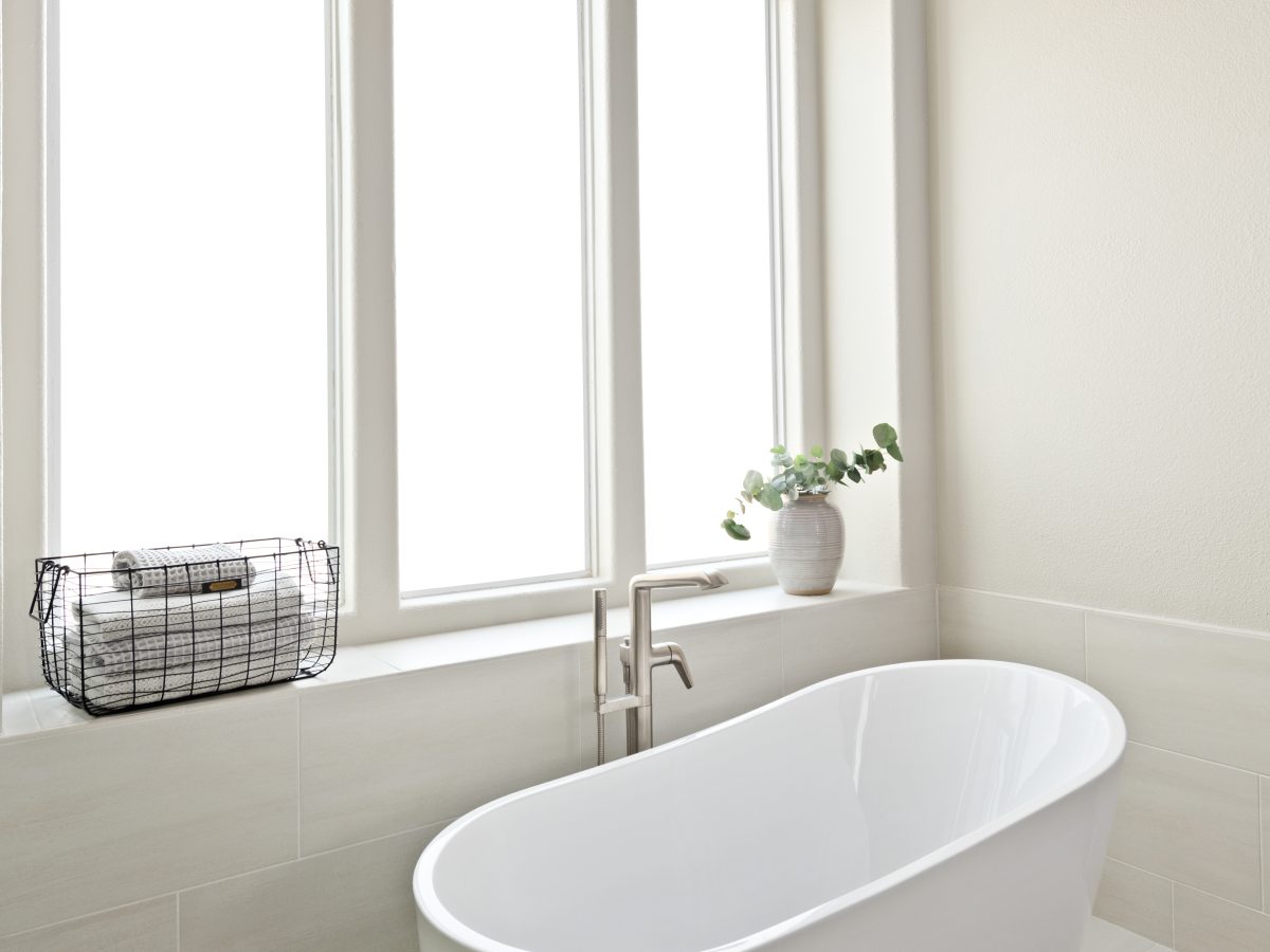 Primary bathroom with freestanding soaking tub, herringbone tile rug, and statement chandelier — Reveal Interior Design Las Vegas