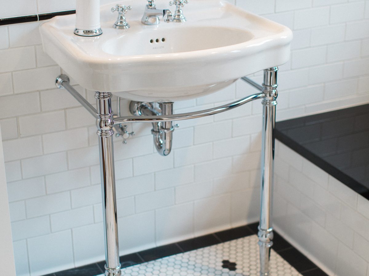 Classic black and white bathroom with hex mosaic floor and freestanding console sink — Reveal Interior Design Las Vegas