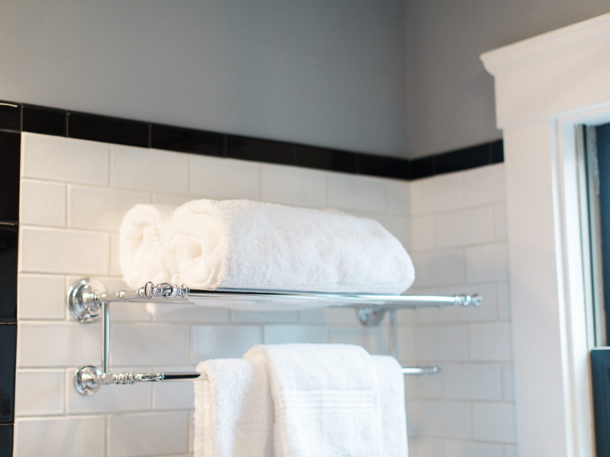 1920s bathroom with white subway tile, black accent trim, and chrome towel rack — Reveal Interior Design Las Vegas