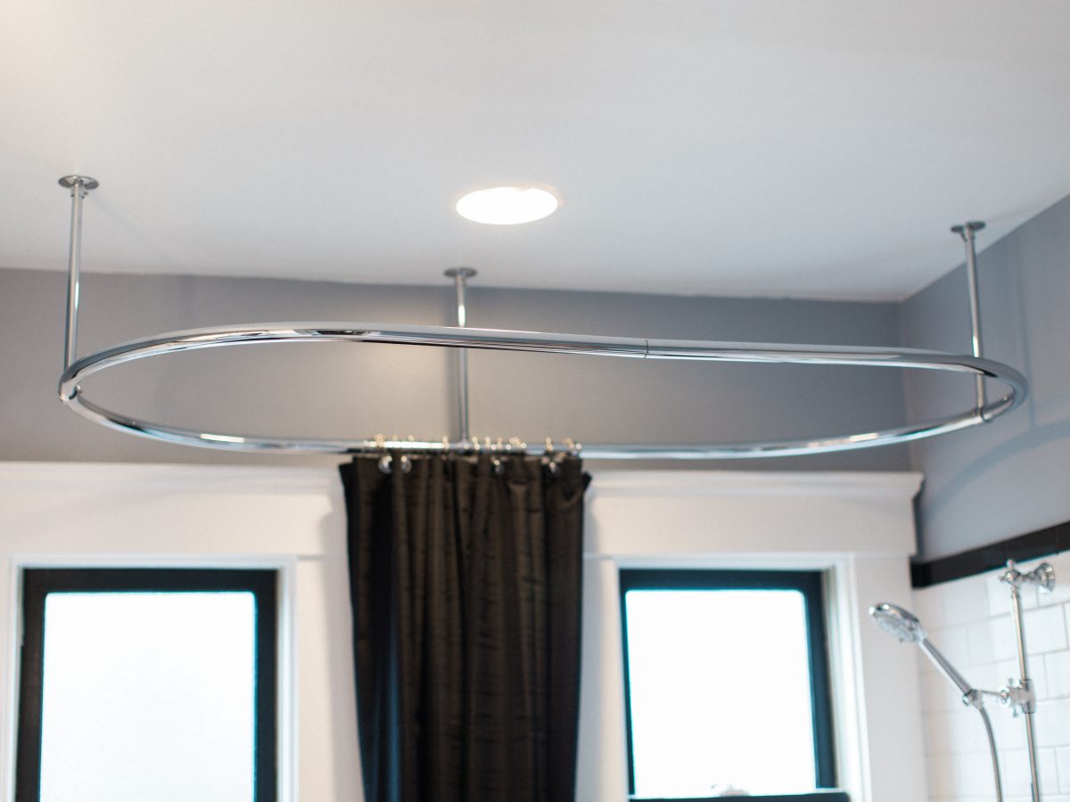 1920s-inspired bathroom with ceiling-mounted oval chrome shower curtain rod and black shower curtain — Reveal Interior Design Las Vegas