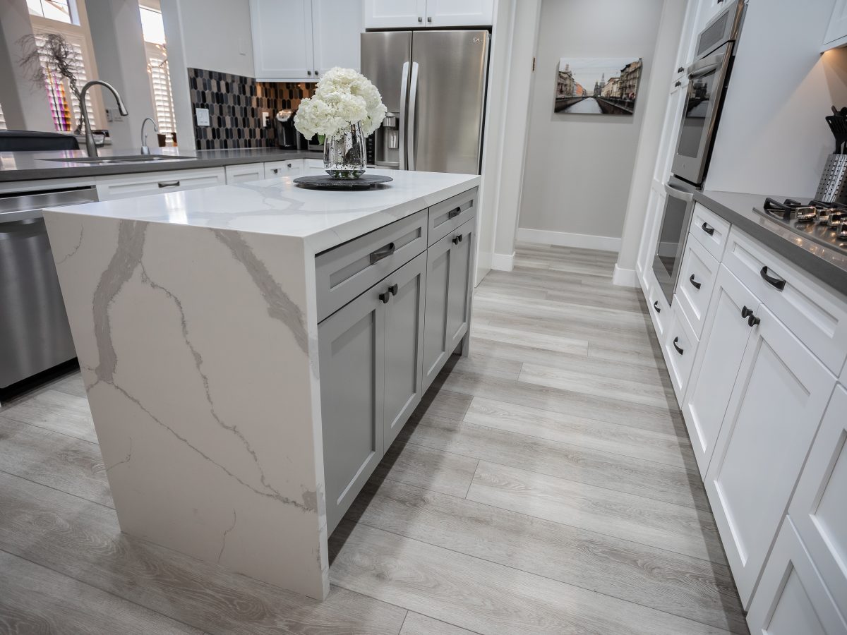Transitional kitchen with Statuario-style quartz dual waterfall island and white shaker cabinetry — Reveal Interior Design Las Vegas