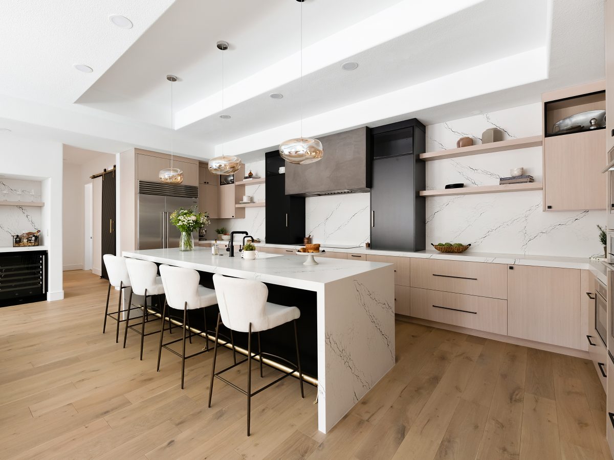 Open-concept kitchen with white-washed oak cabinetry, black quartz countertops, and matte black range hood — Reveal Interior Design Las Vegas