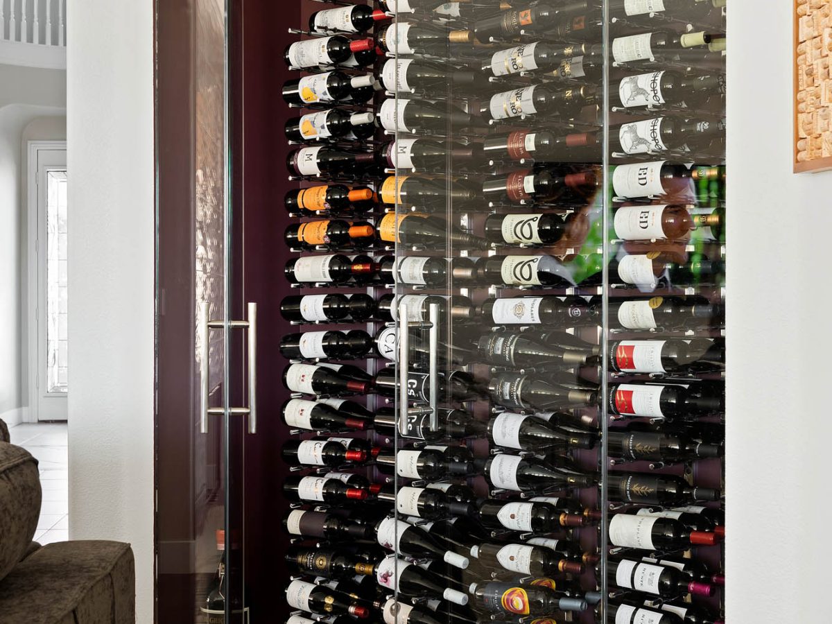 Custom built-in wine storage with glass doors and port wine accent wall — Reveal Interior Design Las Vegas
