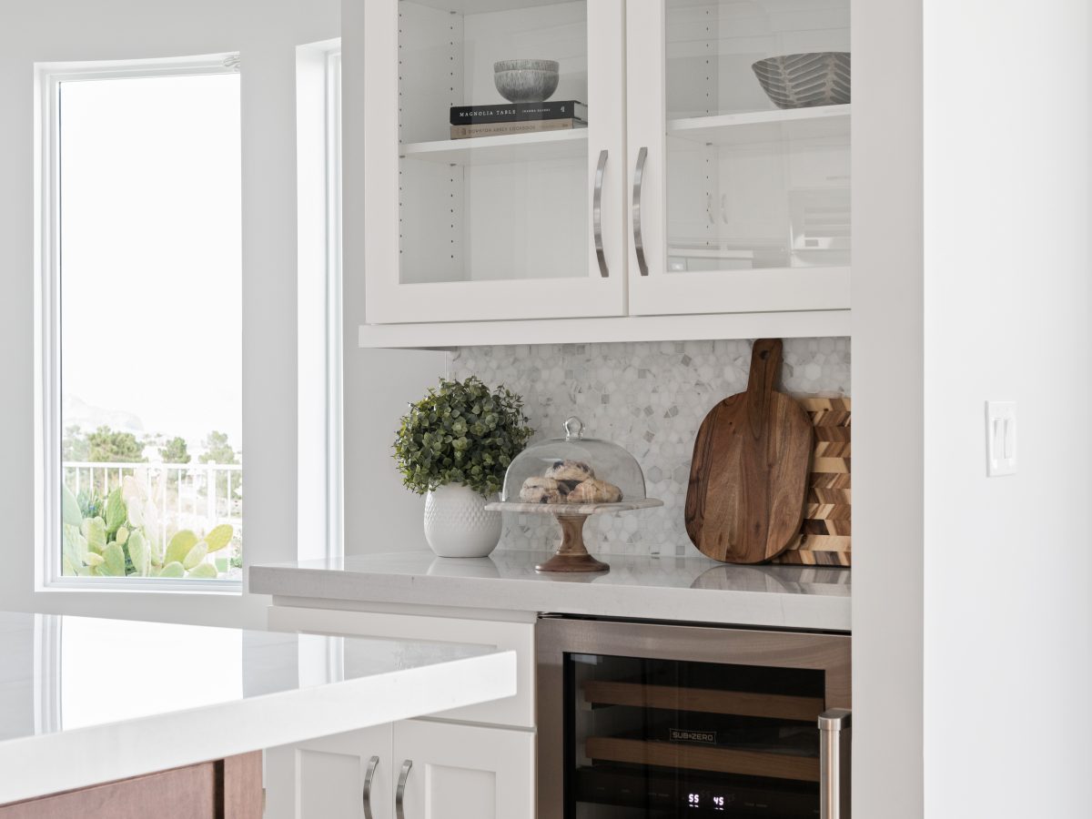 Transitional kitchen butler's pantry with Taj Mahal quartzite countertops and glass-front white cabinetry — Reveal Interior Design Las Vegas